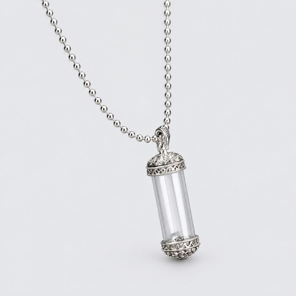 An ornate silver-coloured Victorian vial pendant on a chain.