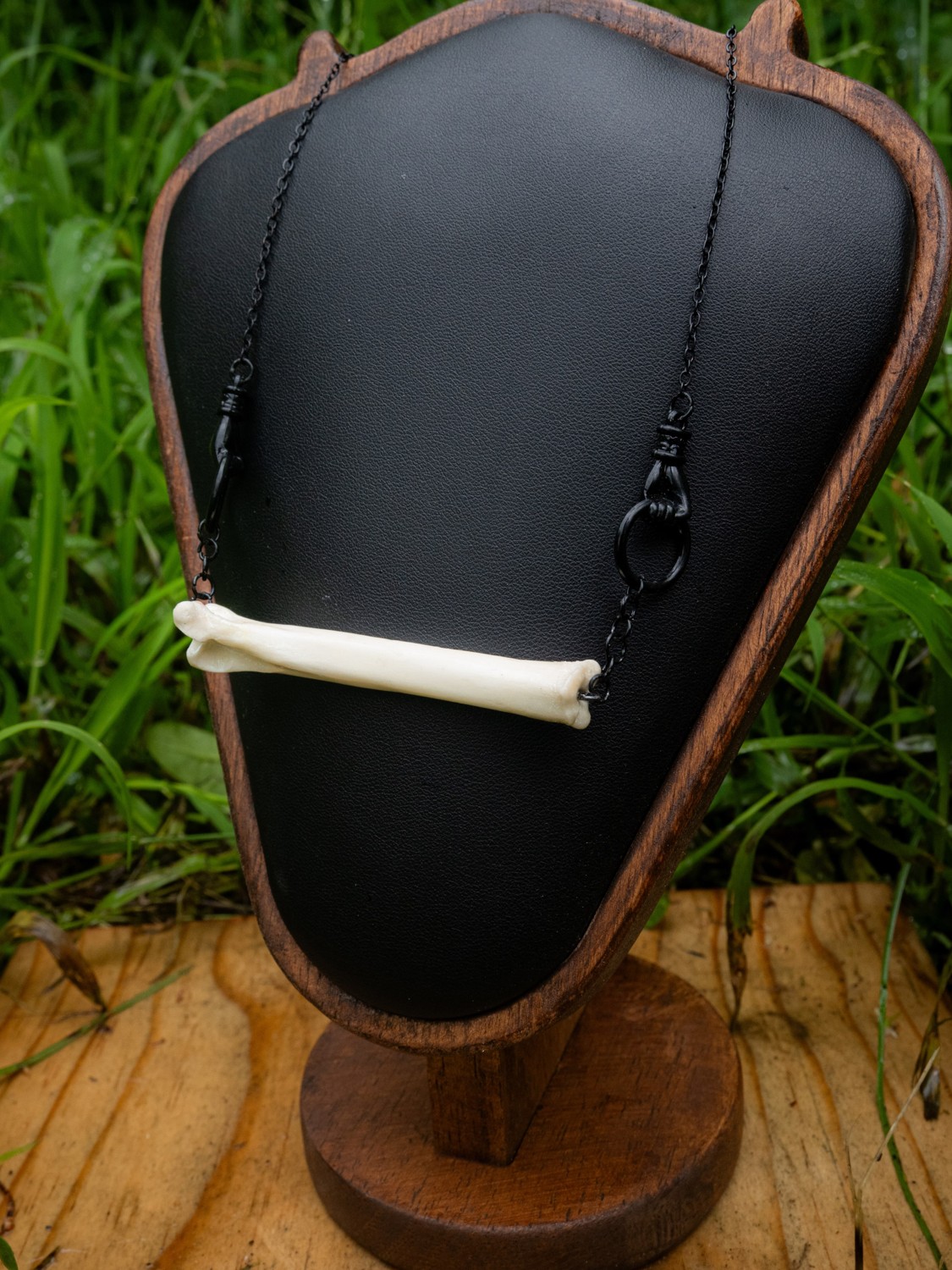 Femur bone necklace · I. A pale femur bone necklace on a dark chain.