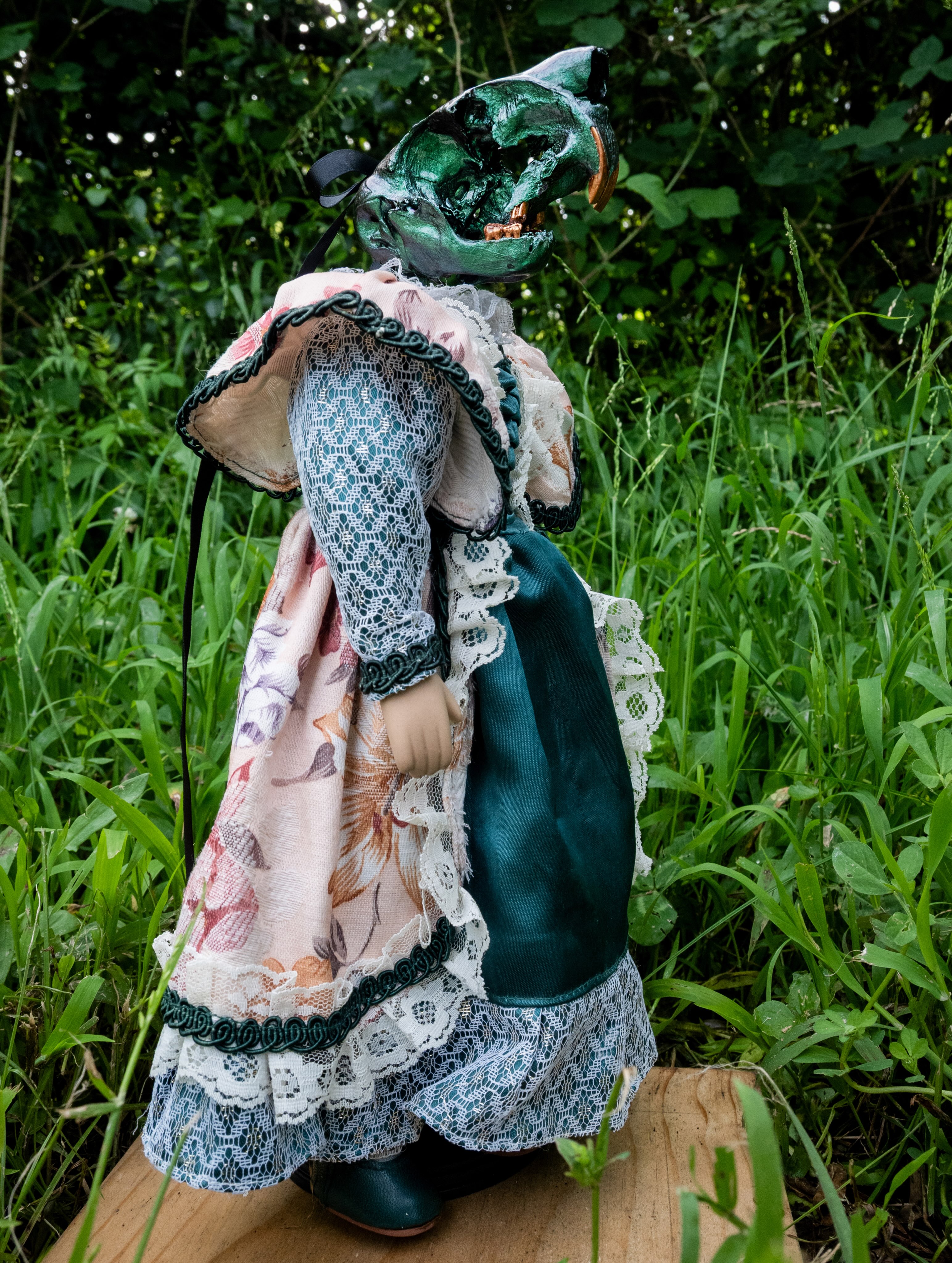 Hester, a green-to-gold chameleon-painted beaver skull on an antique porcelain doll.