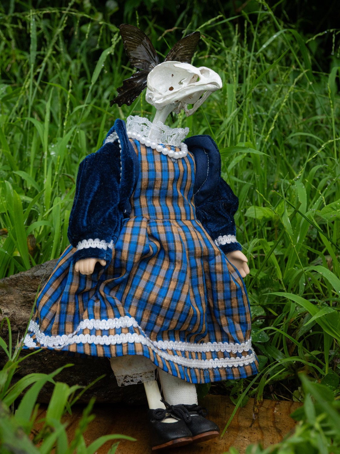 Mabel. A crow skull on an antique porcelain doll with a bone leg and butterfly bow.
