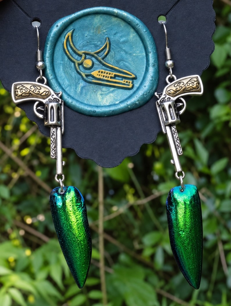 Scarab Beetle earrings with silver-tone revolver-shaped charms.